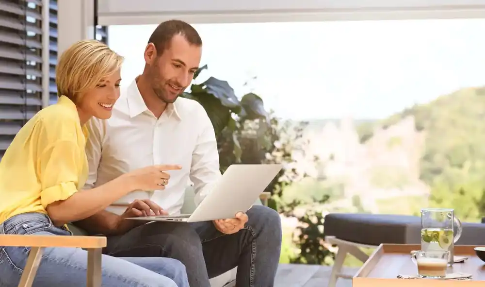 Eine Frau und ein Mann mit Laptop auf einem Outdoorsofa