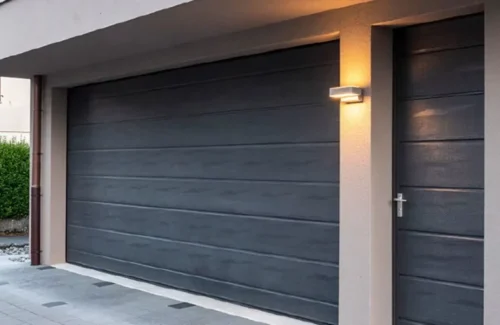 Dunkles Sektionaltor mit passender Seitentür an einer Garage.