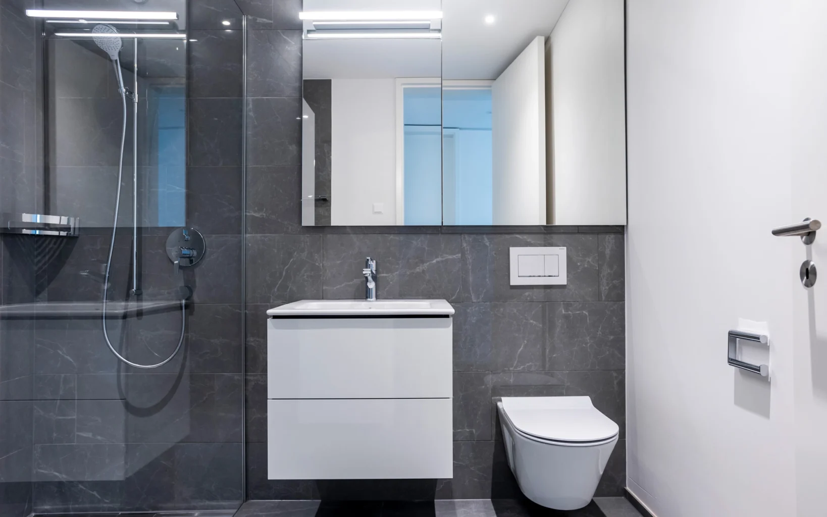 Modernes Badezimmer mit Fliesen in anthrazitfarbener Marmoroptik und Duschkabine aus Glas