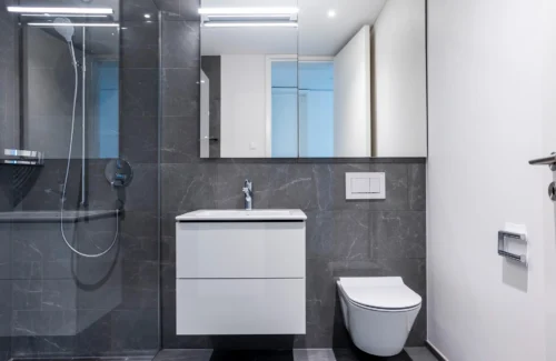 Modernes Badezimmer mit Fliesen in anthrazitfarbener Marmoroptik und Duschkabine aus Glas